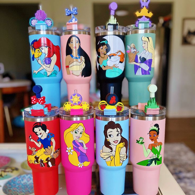 the disney princess tumblers are all lined up on the table in front of each other