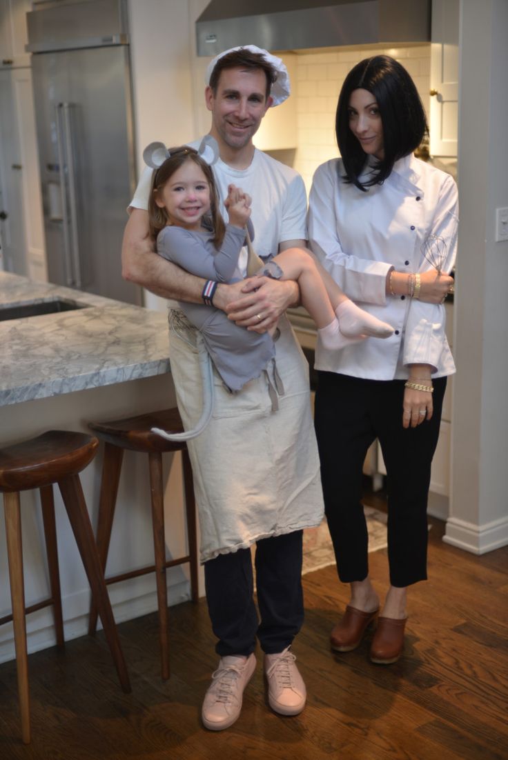 a man and two women are standing in the kitchen holding a baby while wearing bunny ears on their head