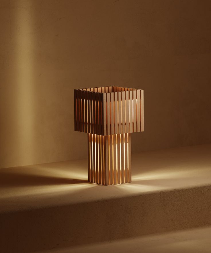 a wooden lamp sitting on top of a table next to a white wall with light coming through it