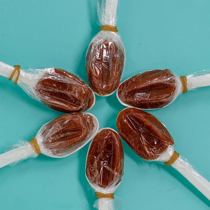 four candies wrapped in plastic sitting on top of a blue tablecloth with white handles