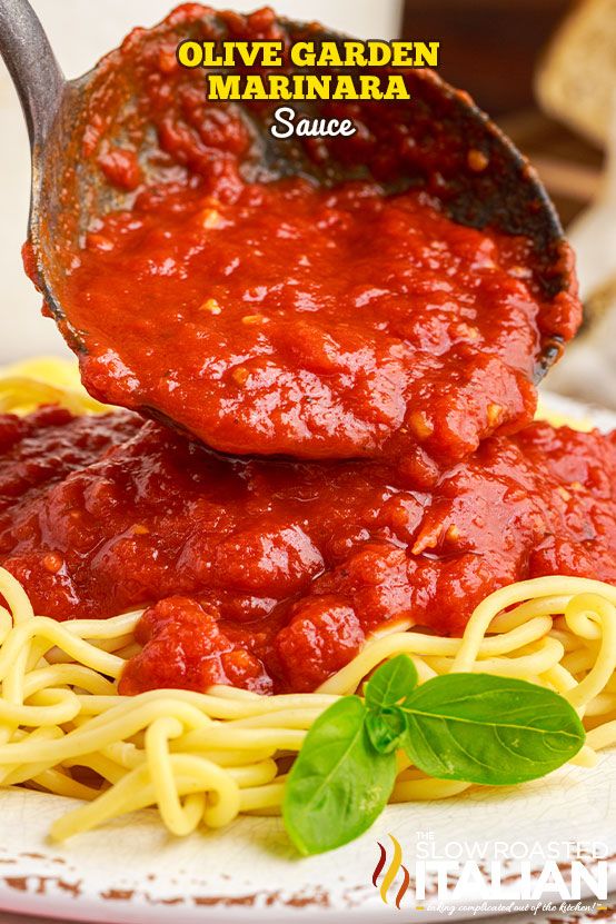 a spoon full of marinara sauce being lifted from a plate with spaghetti on it