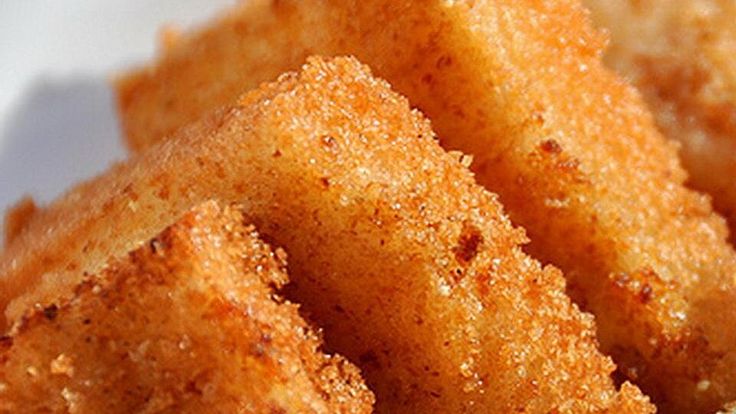 some fried food on a white plate with dipping sauce and lemon wedges next to it