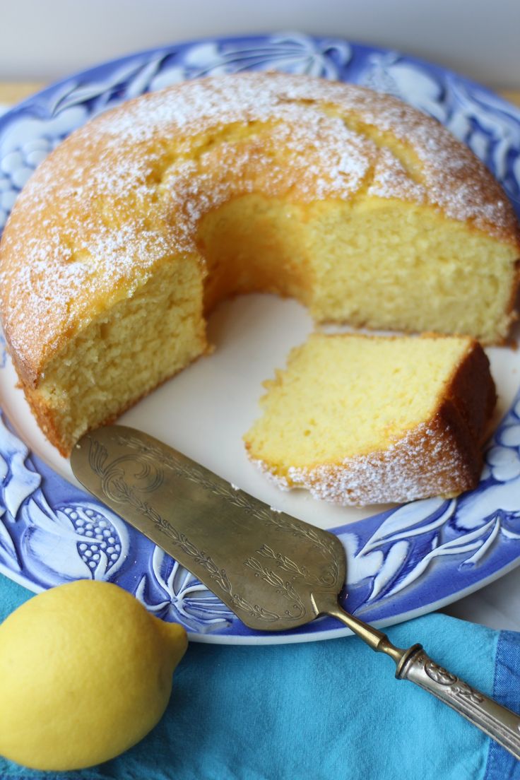 a blue and white plate with a cake on it next to a lemon wedger