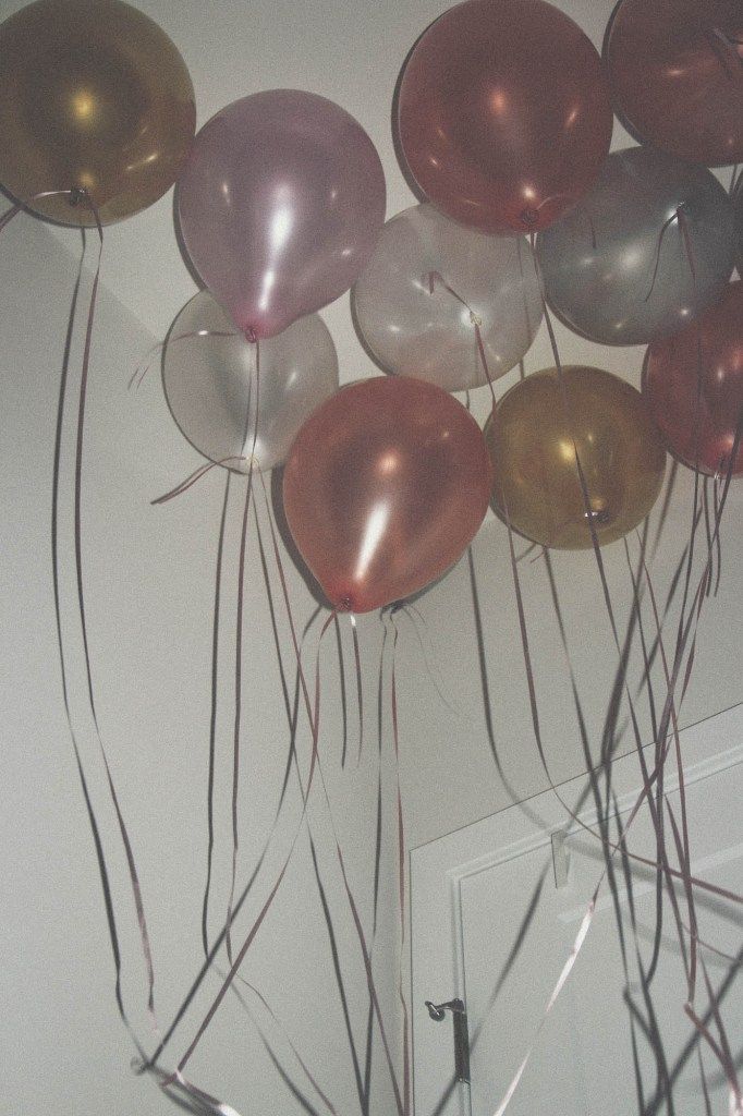 many balloons are floating in the air on a wall above a door with long thin grass