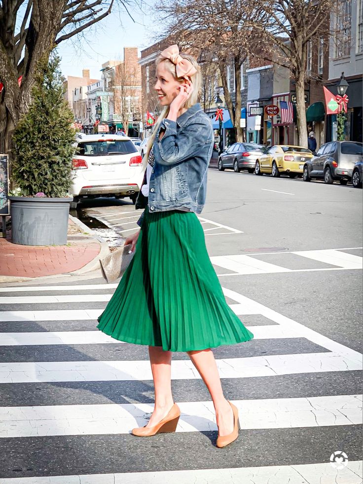 Blonde walking in the city. She is wearing a green pleated a line skirt, a denim jacket, and camel wedge heels. Green Pleated Skirt Outfit Summer, Light Green Skirt Outfit, Turquoise Skirt Outfit, Pleated Skirt Outfit Spring, Green Pleated Skirt Outfit, Pleated Skirt Outfit Summer, Green Skirt Outfits, A Line Skirt Outfits, March Outfits