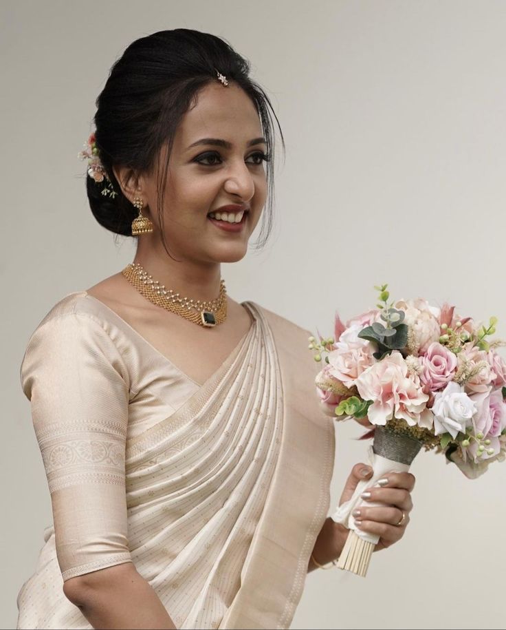 a woman holding a bouquet of flowers in her right hand and smiling at the camera