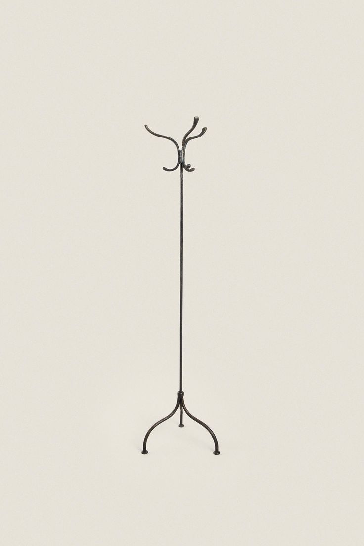 an iron coat stand with three branches on it's top and one branch at the bottom