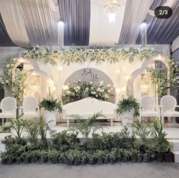 a white stage set up with chairs and plants