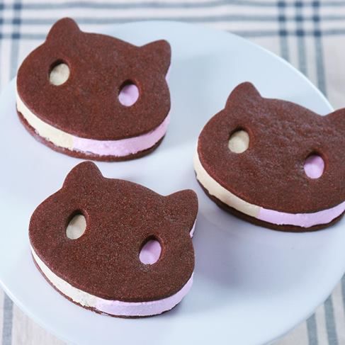 three cookies with pink frosting and a brown teddy bear face on them are sitting on a white plate