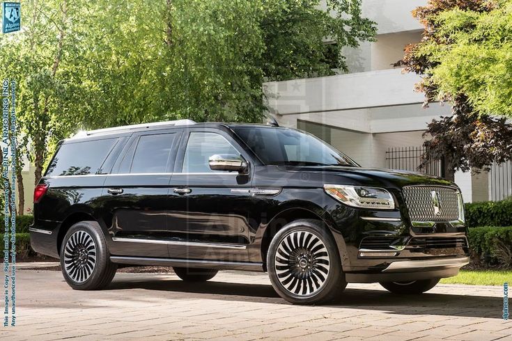 a black suv parked in front of a building with trees and bushes on the side