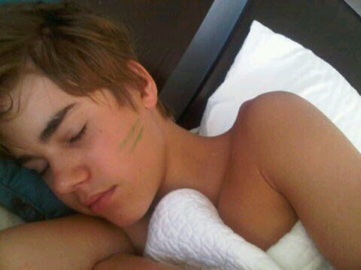 a young man laying in bed with his eyes closed and covered by a white towel