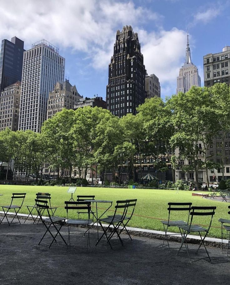 tables and chairs set up in the middle of a park with skyscrapers in the background