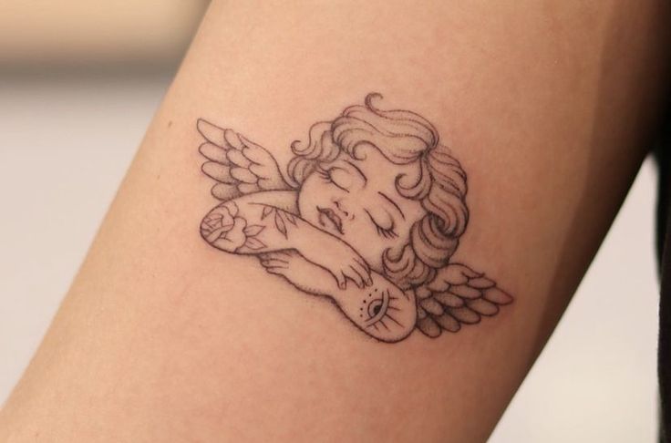 a small tattoo on the arm of a girl with an angel holding a teddy bear