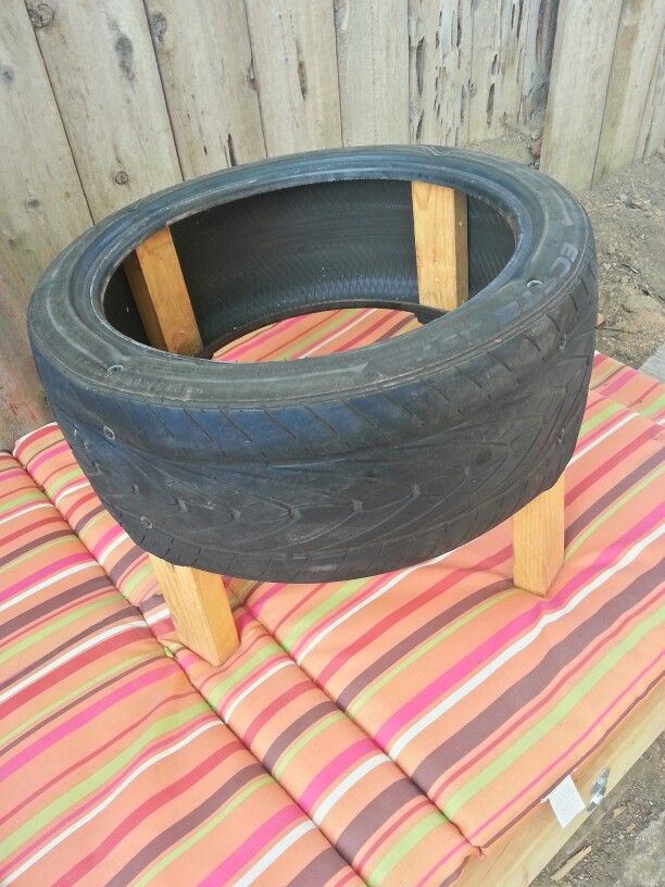 an old tire is sitting on top of a striped cushion in front of a wooden fence