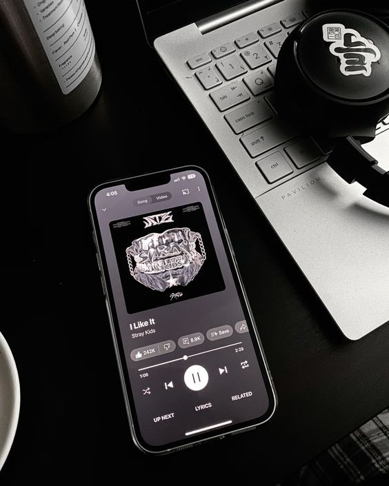 a cell phone sitting on top of a desk next to a keyboard and headphones