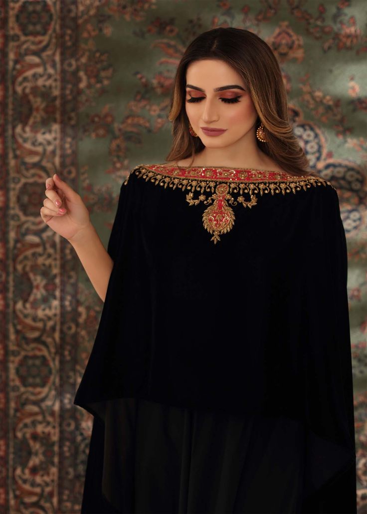 Black velvet cape style top handworked with dabka, tilla and zardozi on the neckline and sleeves. Paired with black flared pants to complete the chic look. Elegant Kurta With Zari Work And Cape Sleeves, Black Sets With Cape Sleeves For Evening, Black Evening Set With Cape Sleeves, Black Evening Sets With Cape Sleeves, Elegant Embroidered Kurta With Cape Sleeves, Evening Embellished Black Palazzo Set, Black Embellished Palazzo Set For Evening, Evening Black Embellished Palazzo Set, Bollywood Style Traditional Drape Evening Tops