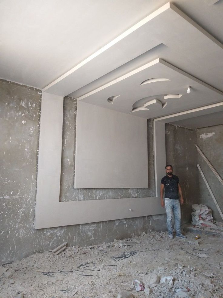 a man standing in the middle of a room with unfinished walls and flooring on it