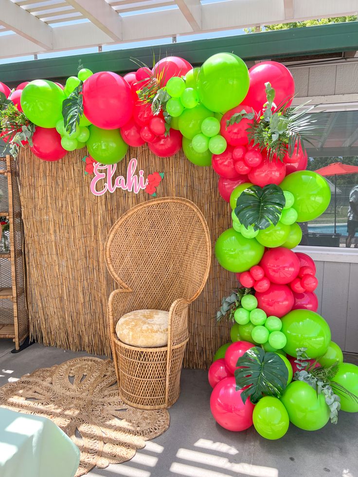 the balloon arch is decorated with green, red and pink balloons