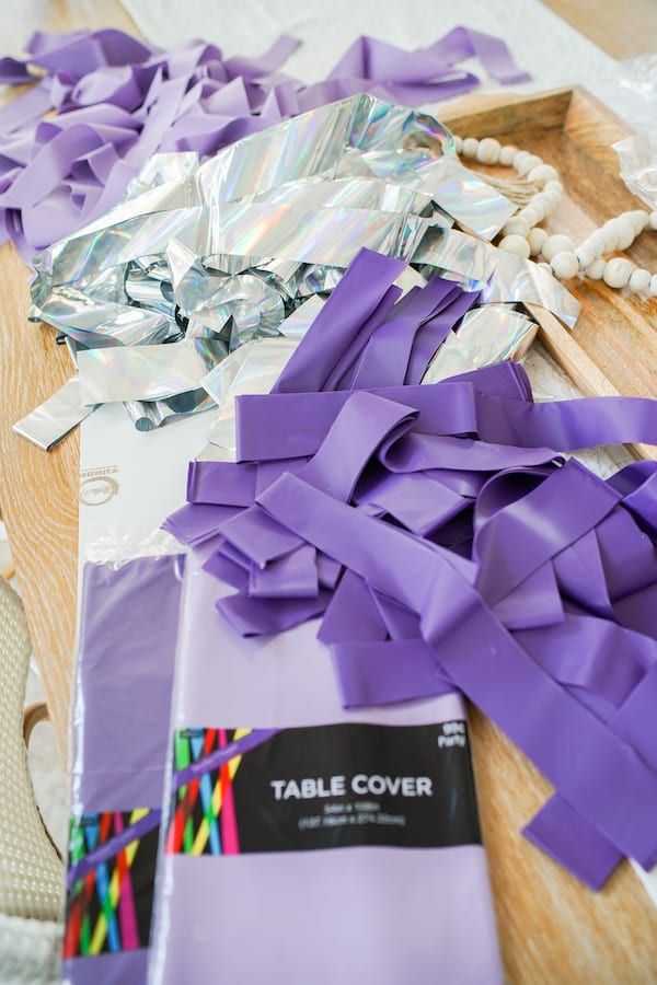 the table is covered with purple ribbons and other crafting supplies, including a piece of tin foil