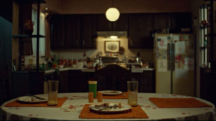 a table with plates and glasses on it in a room that has dark wood cabinets