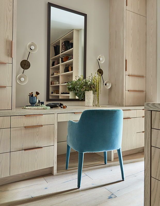 a blue chair sitting in front of a mirror on top of a wooden dresser next to drawers