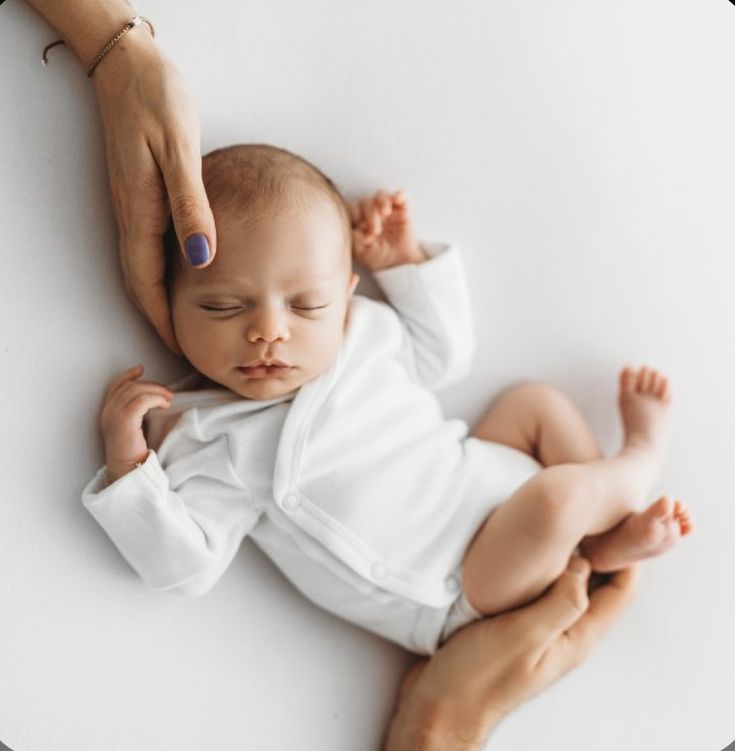 a baby laying on its back being held by a woman's hand