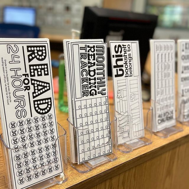 four clear acrylic stands with black and white text on them in front of a computer desk