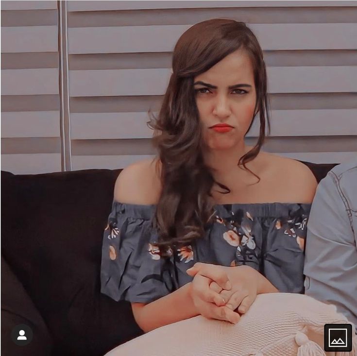 a woman sitting on top of a couch next to a man in a blue shirt