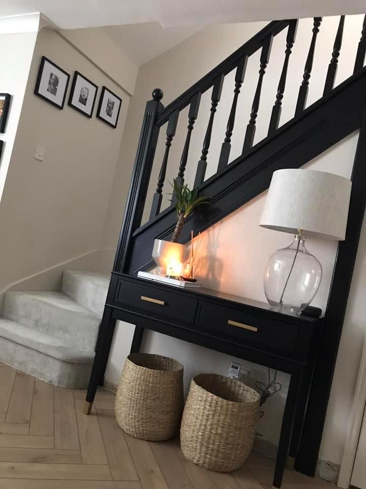 there is a table with two baskets under it and a lamp next to the stairs