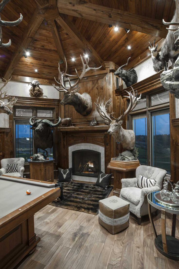 a living room filled with lots of furniture and deer heads on the wall above a fireplace