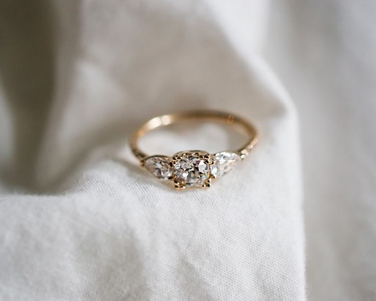 a three stone ring sitting on top of a white cloth