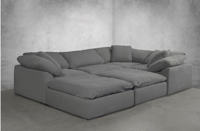 a large gray couch sitting on top of a cement floor next to a white wall