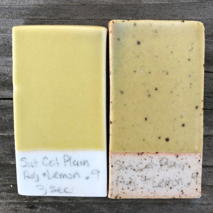 two bars of soap sitting next to each other on top of a wooden table with writing