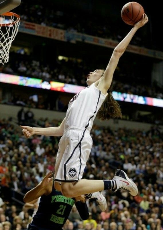 two women playing basketball in front of an audience