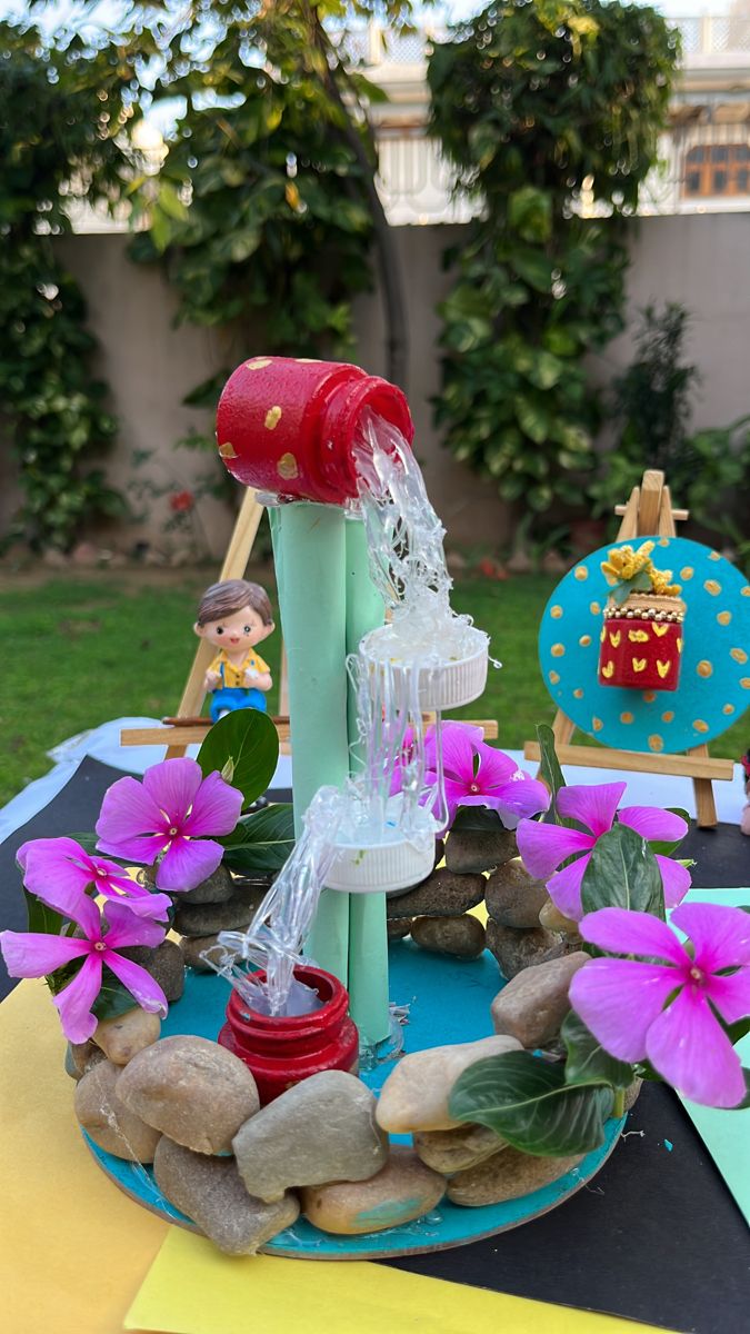 a water fountain made out of rocks and plastic bottles on top of a blue plate