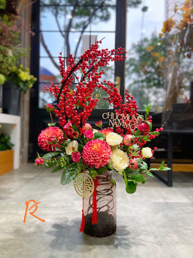 a vase filled with red and white flowers sitting on top of a table next to a sign