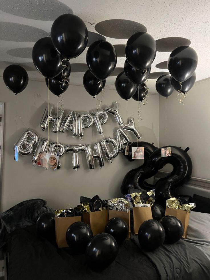 black balloons are hanging from the ceiling in front of a happy birthday sign and gift bags