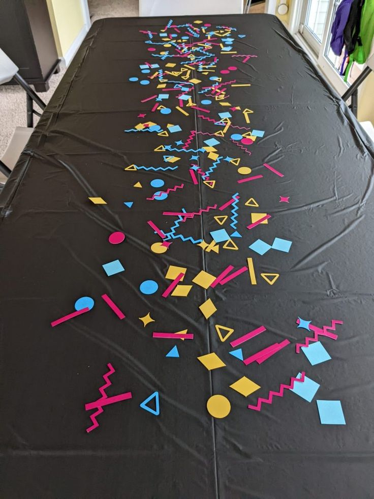 a long table covered in black paper with colorful shapes and lines drawn on the top