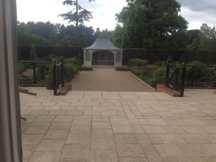 a walkway leading to a white gazebo surrounded by trees