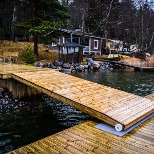 a wooden dock sitting on top of a body of water next to a small house