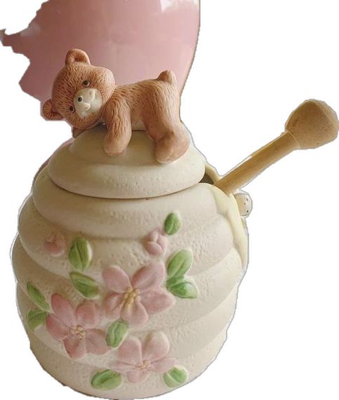 a ceramic figurine of a teddy bear on top of a honey jar