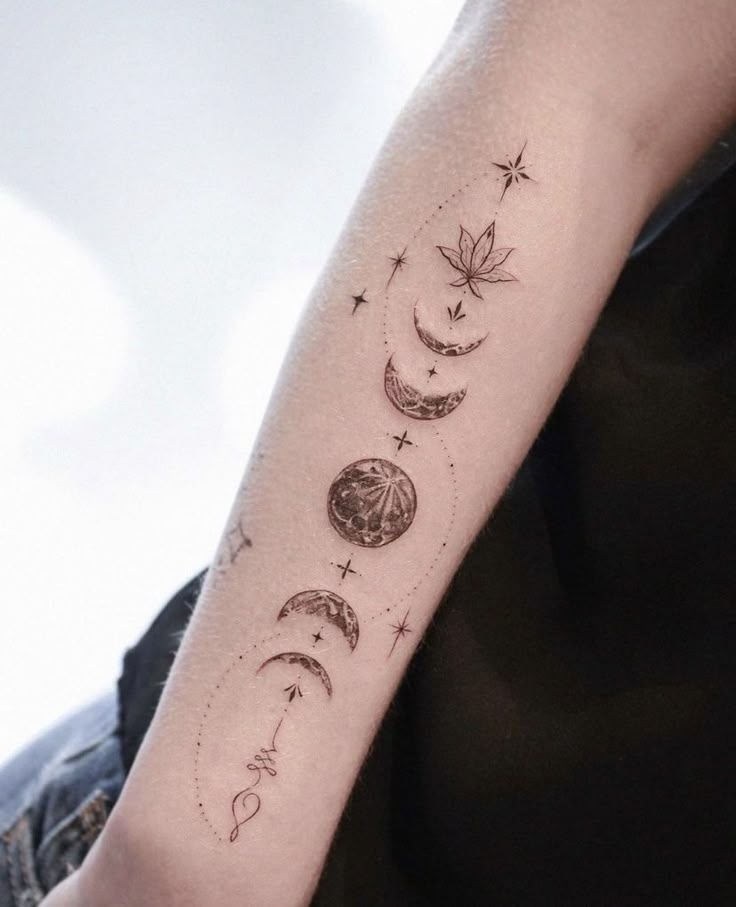 a person with a tattoo on their arm that has phases of the moon and stars