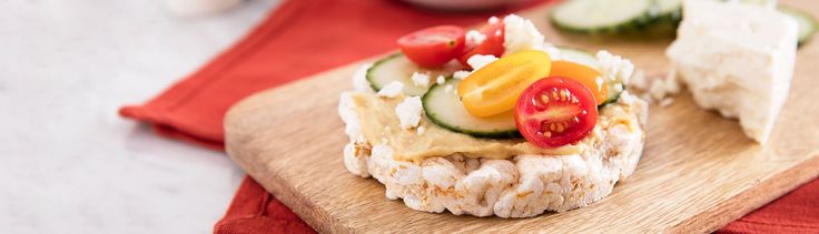 a wooden cutting board topped with cucumber and tomato slices on top of cheese