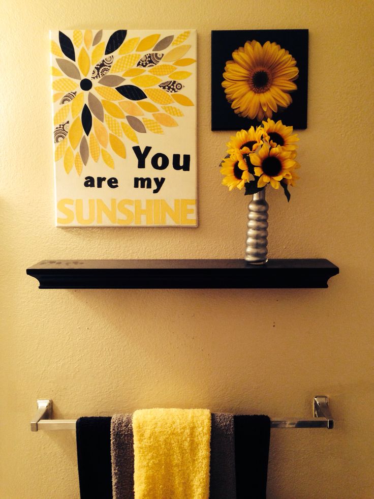 a bathroom with yellow towels and flowers on the shelf above the toilet is decorated with sunflowers