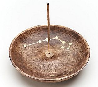 a small wooden bowl with a stick sticking out of it's center and dots on the surface