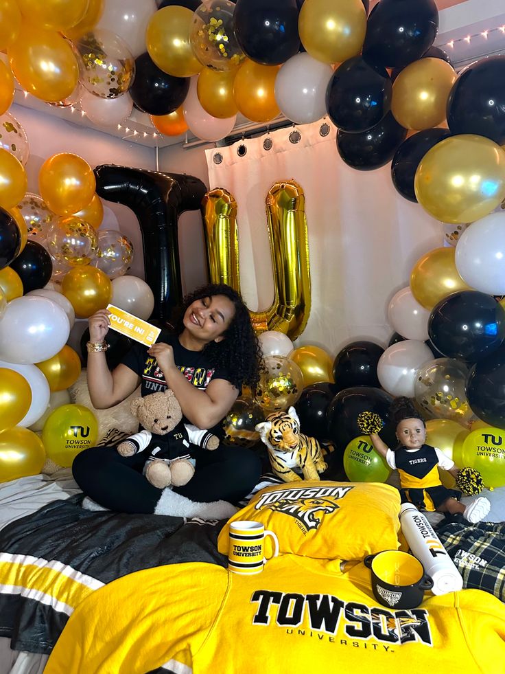 a woman sitting on top of a bed surrounded by balloons