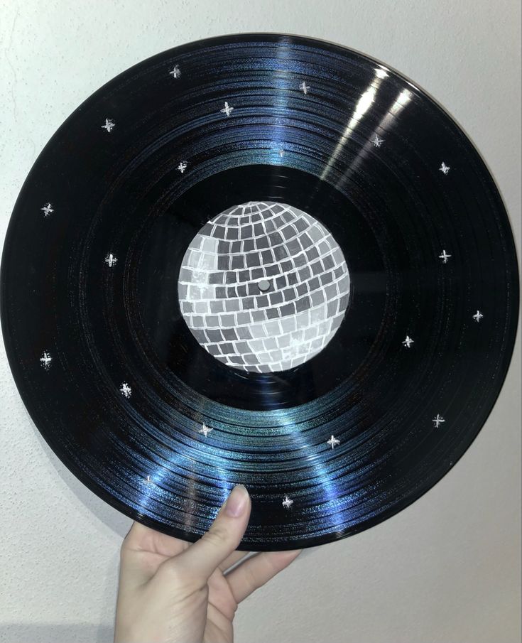 a person holding up a black record with silver stars on it and a disco ball in the center