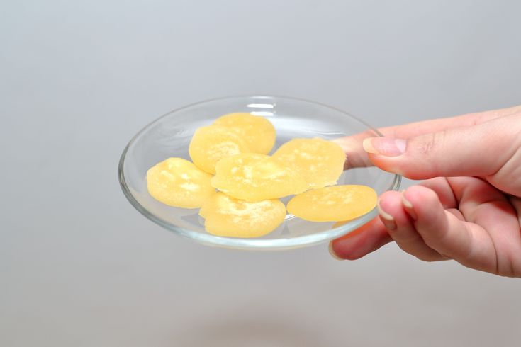 a person holding a glass bowl filled with yellow fruit