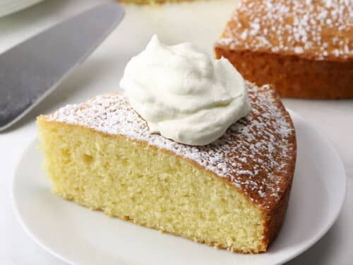 there is a piece of cake on the plate with whipped cream on top and another slice next to it