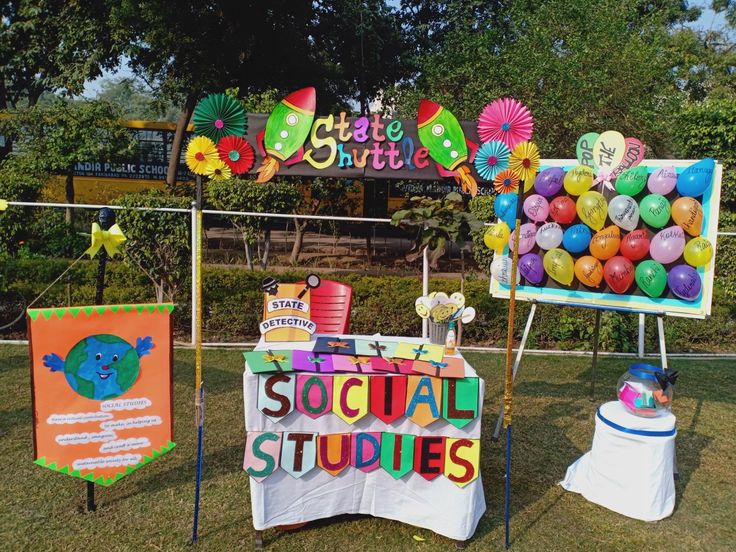 an assortment of colorful balloons and decorations for a social studies event on the lawn in front of a school sign